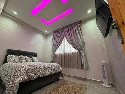 a bedroom with a bed and a window with pink lights at Villa piscine espace vert luxueuse in Oulad Akkou
