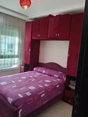 a bedroom with a purple bed and red cabinets at Soyer les biens venus in Oulad Akkou