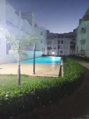 a swimming pool with a palm tree in front of a building at Soyer les biens venus in Oulad Akkou