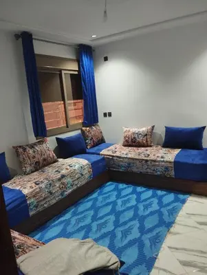 a room with two beds and a blue carpet at L'airoport in Oulad Tayeb