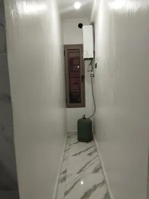 a bathroom with a white wall with a mirror at L'airoport in Oulad Tayeb