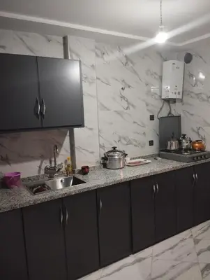 a kitchen with black cabinets and a counter top at L'airoport in Oulad Tayeb