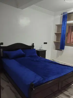 a bed in a bedroom with blue sheets and a window at L'airoport in Oulad Tayeb