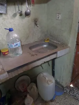a dirty sink with a bottle of water on a counter at la maison du belmokhtar Mansour in Douar Sidi Mohammed