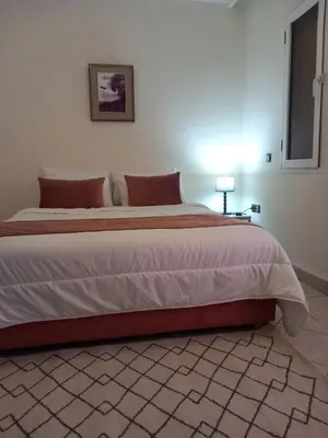 a large bed in a bedroom with a white wall at Alboustane in Oulad Akkou
