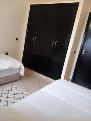 a bedroom with two beds and two black cabinets at Alboustane in Oulad Akkou