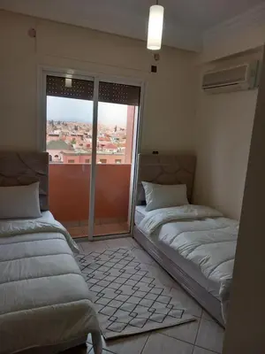 two beds in a room with a large window at Alboustane in Oulad Akkou