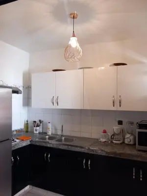 a kitchen with white cabinets and a sink and a light at Alboustane in Oulad Akkou