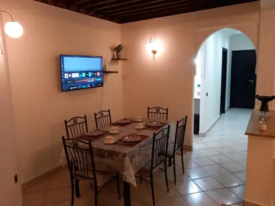 a dining room with a table and chairs and a tv at Alboustane in Oulad Akkou