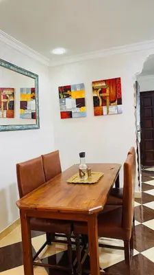 a dining room table with chairs and paintings on the wall at Appartement de luxe à louer à la journée à Tanger Au centre ville in Fès