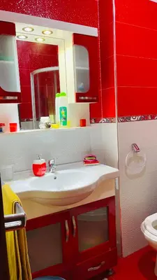 a bathroom with a white sink and a red wall at Appartement de luxe à louer à la journée à Tanger Au centre ville in Fès
