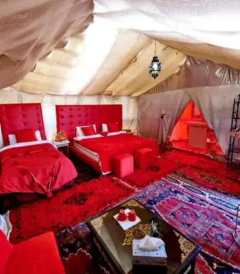 a red bedroom with a bed and a table at Sahara haven camp in Merzouga