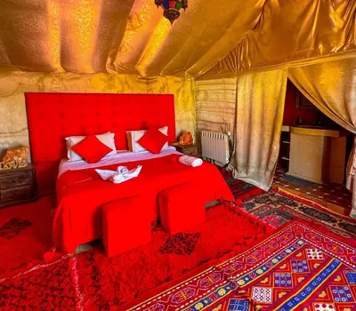 a bedroom with a red bed in a tent at Sahara haven camp in Merzouga