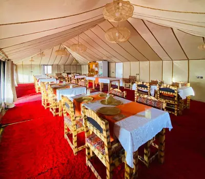 a dining room with tables and chairs in a tent at Sahara haven camp in Merzouga