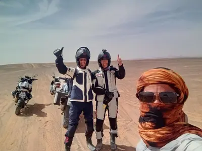 a group of three people standing in the desert at Villasaharamerzouga in Merzouga