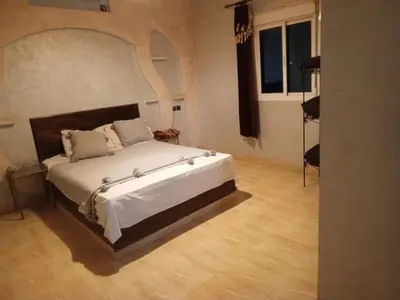 a bedroom with a bed with a large headboard at Villasaharamerzouga in Merzouga
