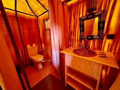 a bathroom with a toilet and a sink with a mirror at Villasaharamerzouga in Merzouga