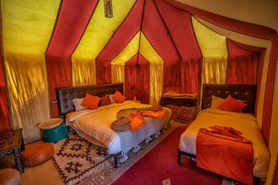two beds in a room with a red and yellow ceiling at Villasaharamerzouga in Merzouga