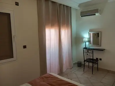 a bedroom with a bed and a chair and a window at Al boustane1 in Oulad Akkou