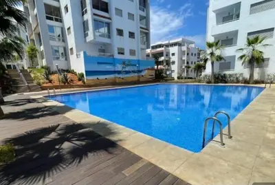 a large blue swimming pool in front of a building at La siesta beach resort in Oulad Akkou