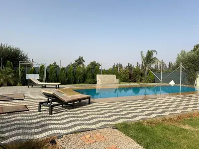 a swimming pool with a bench and a picnic table at Maison au calme avec piscine privé et arboré in Meknès