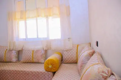a couch with pillows sitting in front of a window at Appartement du luxe in Oulad Akkou