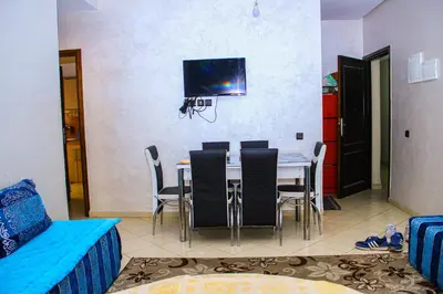 a dining room with a table with chairs and a tv at Appartement du luxe in Oulad Akkou