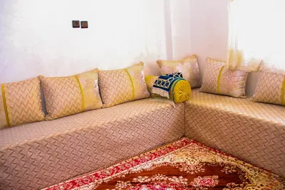 a couch with pillows on it in a room at Appartement du luxe in Oulad Akkou