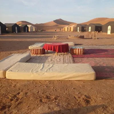 a group of beds in the middle of the desert at قصر الركابي in Mhamid