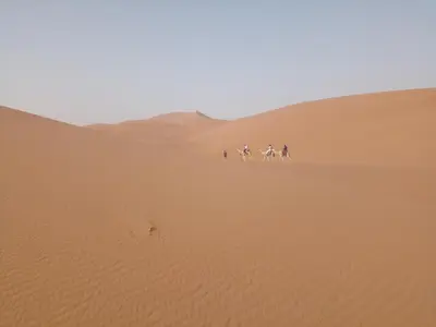 a group of people riding bikes in the desert at قصر الركابي in Mhamid