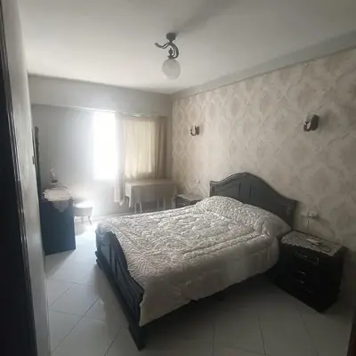 a bedroom with a bed and a table and a window at Res zin el mahabba in Oulad Akkou
