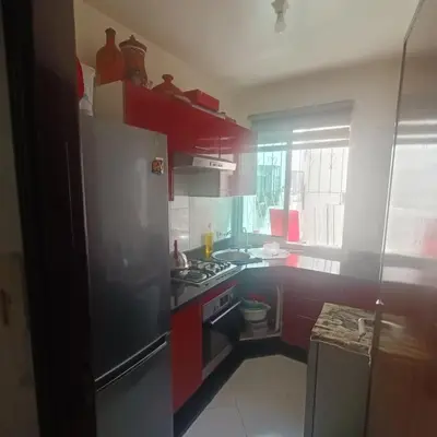 a kitchen with red cabinets and a stainless steel refrigerator at Res zin el mahabba in Oulad Akkou