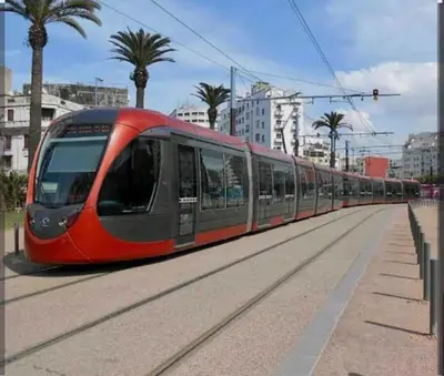 a red train on the tracks in a city at Res zin el mahabba in Oulad Akkou