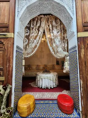 a room with a table and two ottomans at Riad Bennouna in Fès