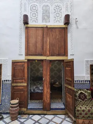 a wooden bed in a room next to a wall at Riad Bennouna in Fès