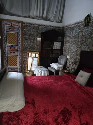 a bedroom with a large bed with a red blanket at Riad Bennouna in Fès