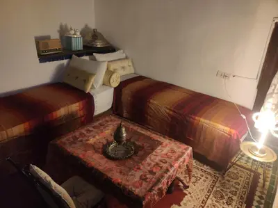 a room with two beds and a table and a lamp at Riad Bennouna in Fès