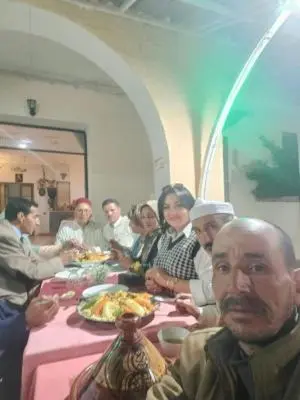 a group of people sitting at a table eating food at Hôtel des cedres azrou in Oulad Akkou