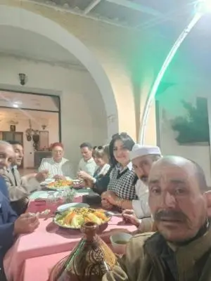 a group of people sitting at a table eating food at Hôtel des cedres azrou in Oulad Akkou