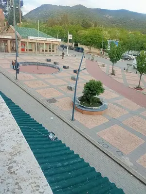 a street with a water fountain in a city at Hôtel des cedres azrou in Oulad Akkou