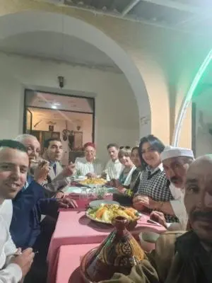 a group of people sitting at a table eating food at Hôtel des cedres azrou in Oulad Akkou