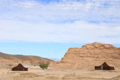 two huts in the desert under a cloudy sky at Campement Akka Nait Sidi - Tissint in Tissint