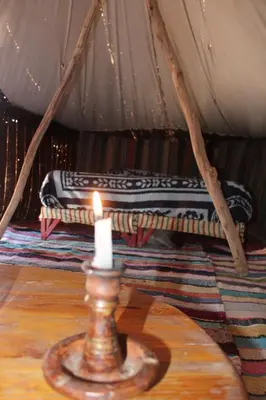 a candle on a table in a tent with a mattress at Campement Akka Nait Sidi - Tissint in Tissint