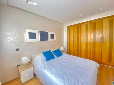 a bedroom with a bed with blue pillows on it at Superbe appart central in Oulad Akkou