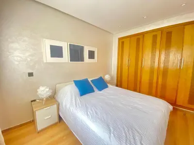 a bedroom with a bed with blue pillows on it at Superbe appart central in Oulad Akkou
