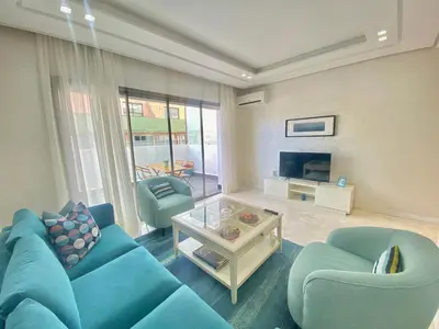 a living room with a blue couch and two chairs at Superbe appart central in Oulad Akkou