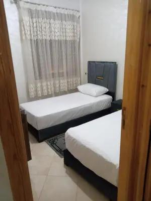 two beds in a room with a window at Appartement Confortable à Louer in Oulad Akkou