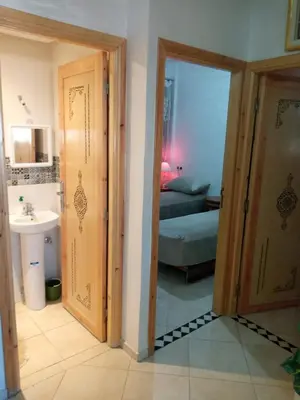 a bathroom with a sink and a door to a room at Appartement Confortable à Louer in Oulad Akkou