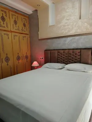 a large white bed in a room with a lamp at Appartement Confortable à Louer in Oulad Akkou