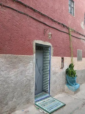 a door in the side of a red building at house Merinides fes in Fès